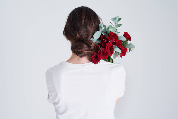 Buď jako růže, silná a něžná. Studio záběr nerozpoznatelné ženy držící květiny na šedém pozadí. - Fotografie, Obrázek
