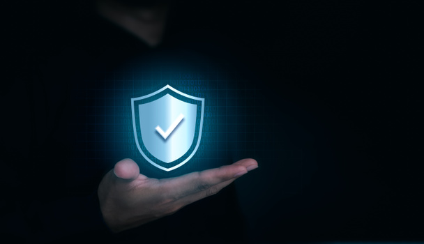 A virtual shield lock icon with the correct sign appeared on the human's hand on dark background with copy space. Cyber security, data protection, business privacy technology concept. - Photo, Image