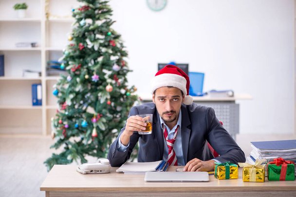 Fiatal férfi alkalmazott ünnepli a karácsonyt a munkahelyen - Fotó, kép