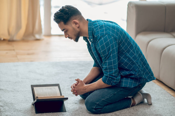 Young muslim praying at home and reading Quran - Valokuva, kuva