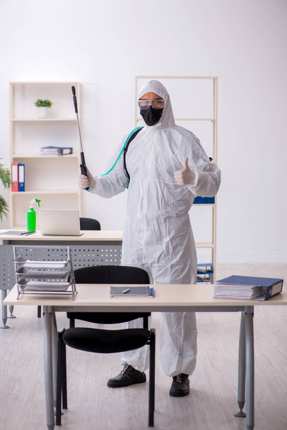 Contratista masculino joven desinfectando oficina durante pandemia - Foto, Imagen