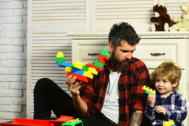 Loving dad and little boy child have fun play build construct with wooden blocks bricks. Father and son create toys from bricks. Dad and kid build of plastic blocks. - Фото, изображение