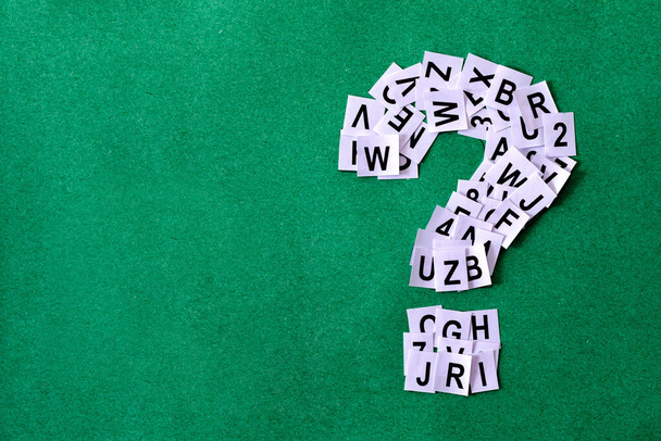 Question mark on green background with copy space made of paper with letters and numbers minimal concept of finding help answering problem analysis and learning. - Foto, imagen