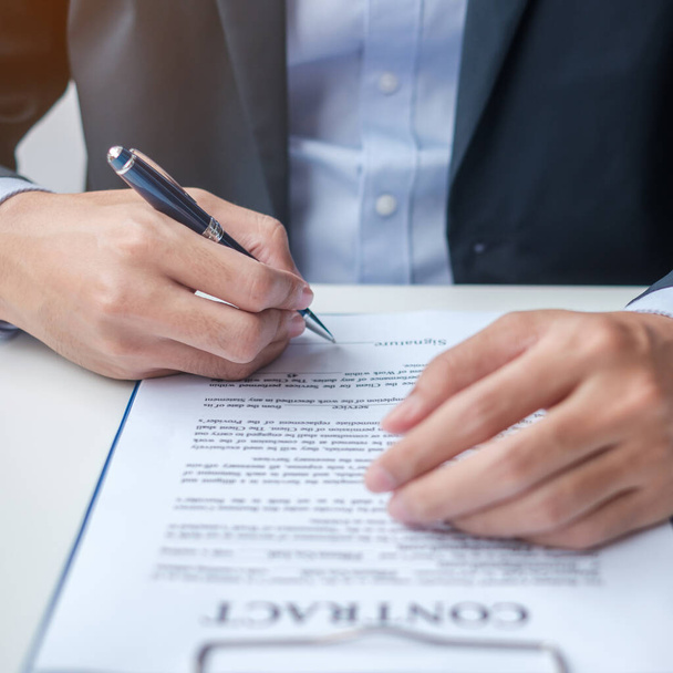 Businessman signing on contract documents after reading, man holding pen and approve on business report. Contract agreement, partnership and deal concepts - Foto, immagini