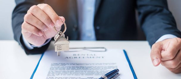 Mann mit Hausschlüssel bei der Unterzeichnung von Hausvertragsdokumenten. Vertragsabschluss, Immobilien, Kauf und Verkauf sowie Versicherungskonzepte - Foto, Bild