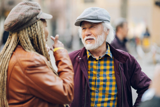 Foto von fröhlichen positiven alten Mann alte Frau multirassischen Paar genießen gute Laune Lächeln im Freien im Stadtpark. - Fokus auf den Menschen - - Foto, Bild