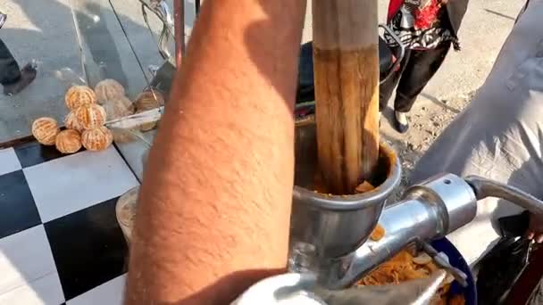 Straßenstand Nahaufnahme einer männlichen Hand, die mit einer Saftpresse frische Orangen presst, gesundes Frühstück, Energy-Drink, frischer Saft pakistanisch und indisches Streetfood - Filmmaterial, Video