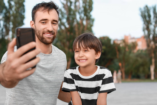 Padre con su pequeño hijo tomando selfie al aire libre - Foto, imagen