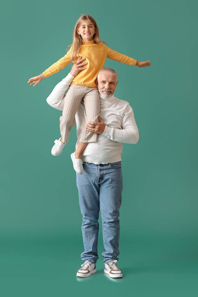 klein meisje met haar grootvader op groene achtergrond - Foto, afbeelding