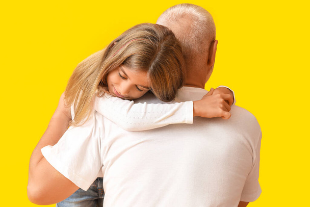 Bambina che abbraccia il nonno su sfondo giallo - Foto, immagini