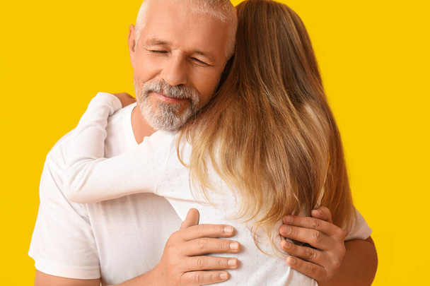 Senior man hugging his little granddaughter on yellow background - Foto, Imagen