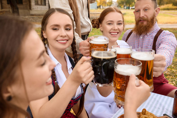 Люди с пивом празднуют Октоберфест на открытом воздухе - Фото, изображение
