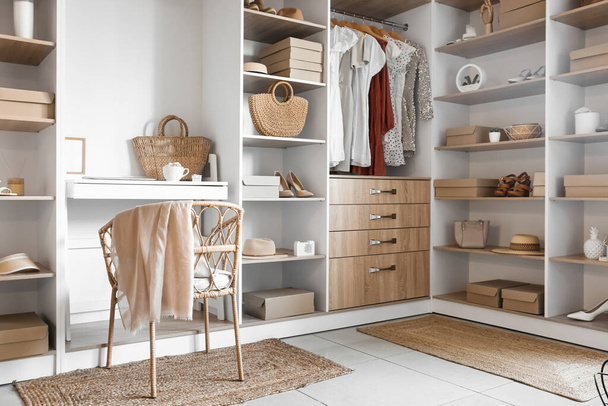 Interior of modern wardrobe with shelves and workplace - 写真・画像