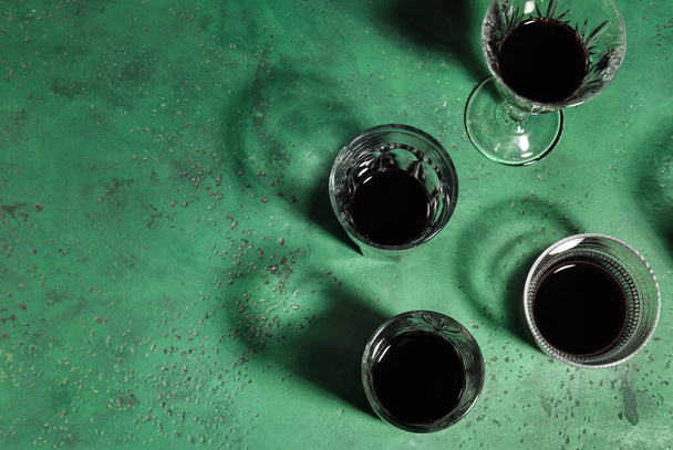 Different glasses with alcohol on green background - Foto, afbeelding