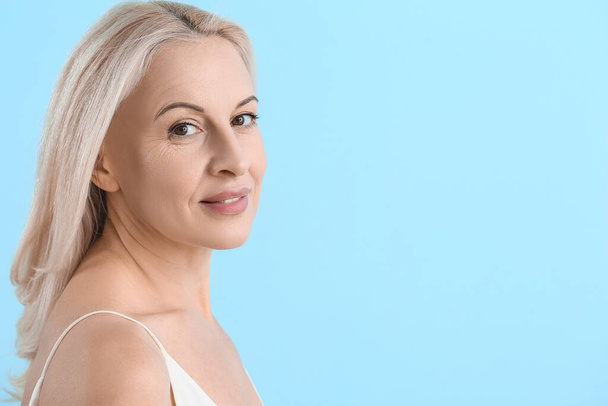 Ältere blonde Frau mit gesunder Haut auf blauem Hintergrund - Foto, Bild