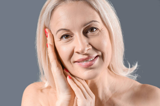 volwassen blonde vrouw met gezonde huid op donkere achtergrond, close-up - Foto, afbeelding