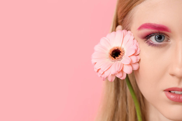Young woman with creative eyebrows and gerbera flower on color background - Φωτογραφία, εικόνα
