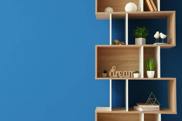 Wooden shelving unit with books and decor near blue wall - Photo, Image