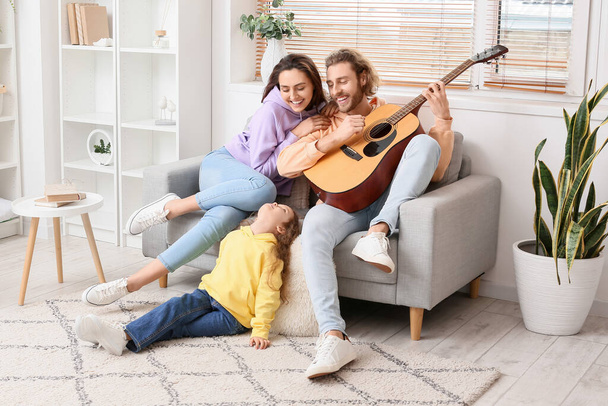 Happy young family playing guitar at home - Фото, изображение