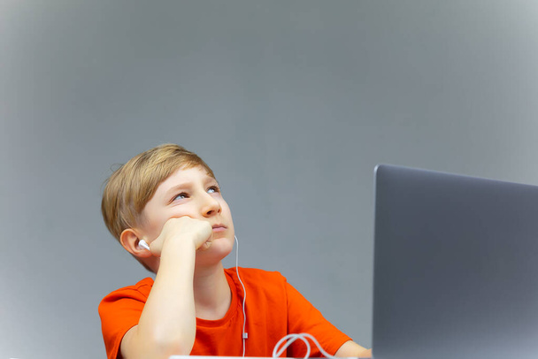 un chico sentado en un portátil pensando y mirando hacia arriba - Foto, Imagen