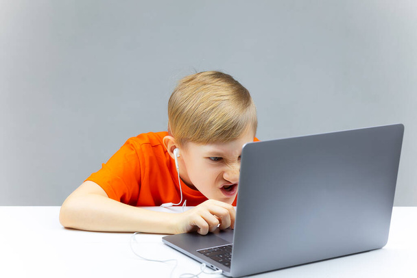 das Kind arbeitet hart am Laptop und hört Musik über Kopfhörer - Foto, Bild