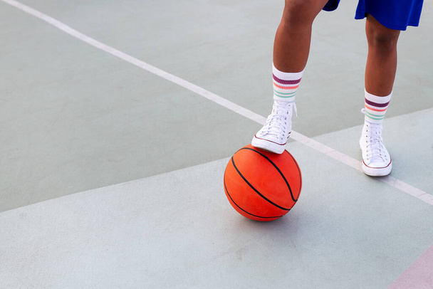 foot of an unrecognizable person holding a basketball on the court, concept of urban sport in the street, copy space for text - Фото, изображение