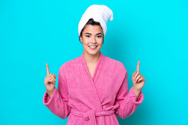 Young Brazilian woman with a bathrobe isolated on blue background pointing up a great idea - Fotó, kép