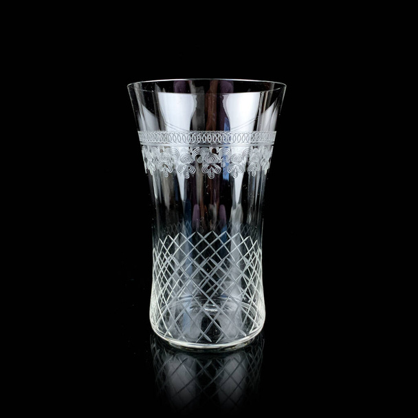 antique glass tumbler. vintage glass with engraving on a black isolated background - Photo, Image