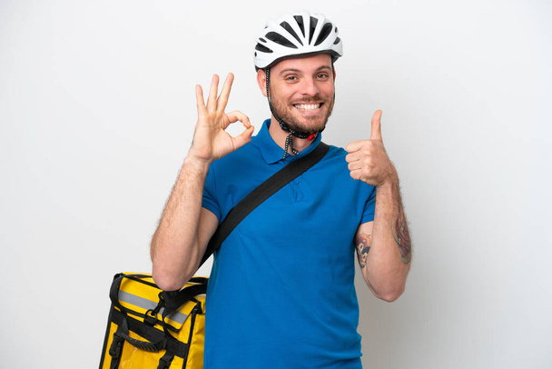 Joven brasileño con mochila térmica aislado sobre fondo blanco mostrando signo de ok y el pulgar hacia arriba gesto - Foto, Imagen