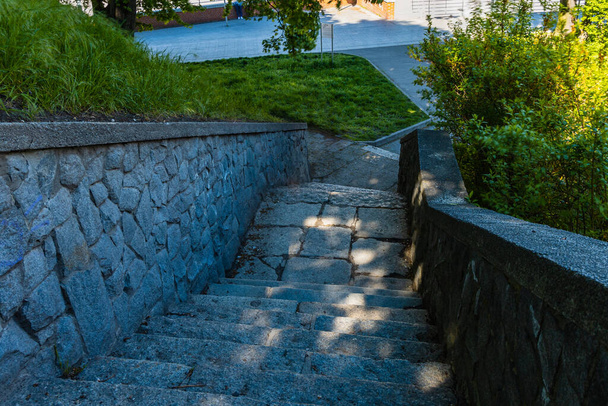 Stony stairs with green grass and bushes around and sunlight from space between tree leaves - Foto, afbeelding