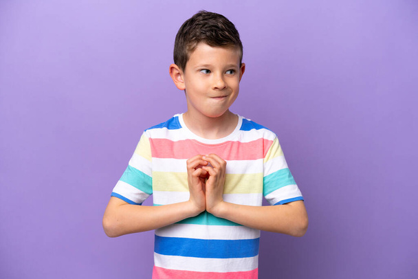 Malý chlapec izolovaný na fialovém pozadí intrikující něco - Fotografie, Obrázek