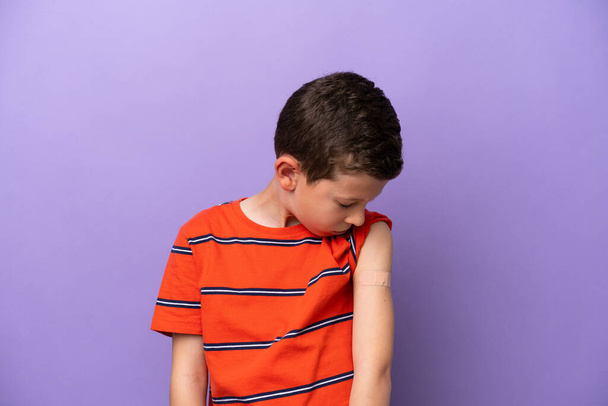 Malý chlapec nosí náplast izolované na fialovém pozadí s veselým výrazem - Fotografie, Obrázek