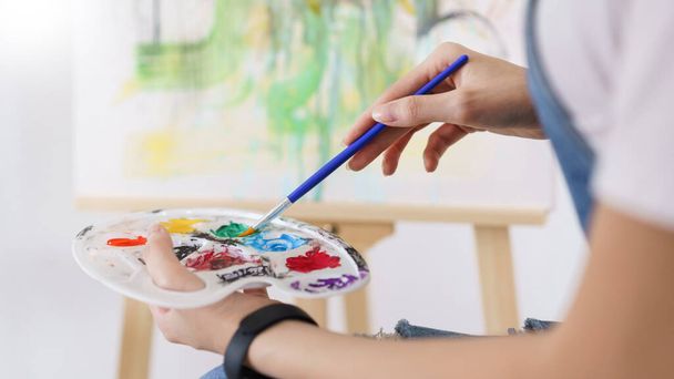 Kreative Kunstkonzept, Hand der jungen asiatischen Frau halten Pinsel, um in Palette für die Malerei eintauchen. - Foto, Bild