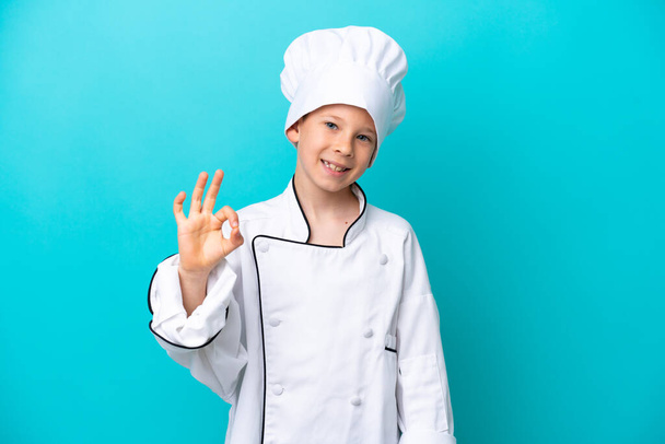 Chef chico aislado sobre fondo azul mostrando signo ok con los dedos - Foto, Imagen