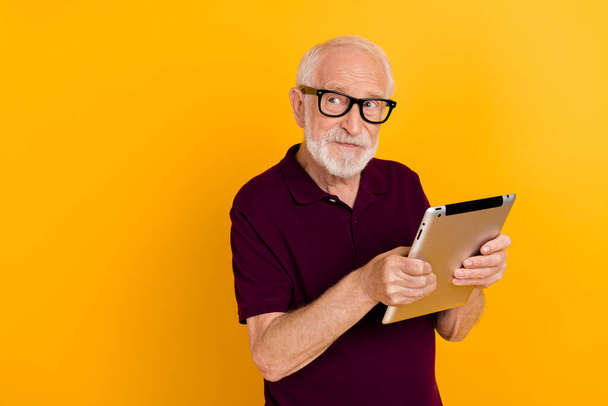 Photo of aged man use tablet think dream idea look empty space isolated over yellow color background - Φωτογραφία, εικόνα