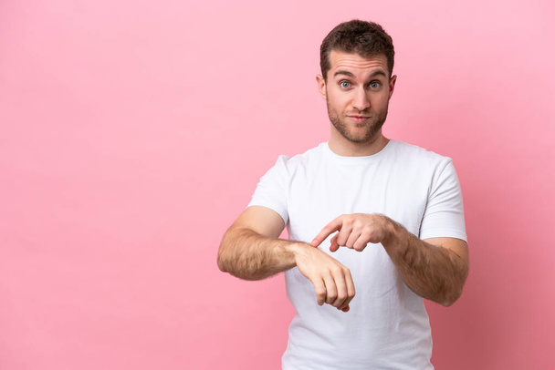 Young caucasian man isolated on pink background making the gesture of being late - Photo, Image