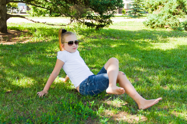 Smiling girl in sunglass with sore knee - Foto, afbeelding
