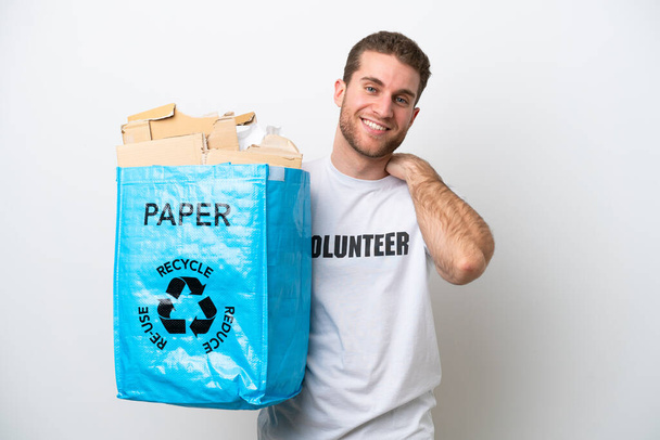 Νεαρός καυκάσιος που κρατάει μια σακούλα ανακύκλωσης γεμάτη χαρτί για να ανακυκλώσει απομονωμένος σε λευκό φόντο γελώντας - Φωτογραφία, εικόνα