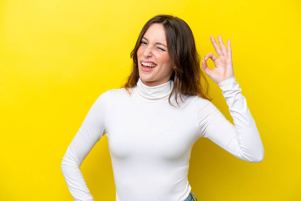 Young caucasian woman isolated on yellow background showing ok sign with fingers - Photo, Image