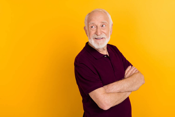 Photo of funky elder man crossed arms look promo wear dark t-shirt isolated on yellow color background - Foto, Imagen