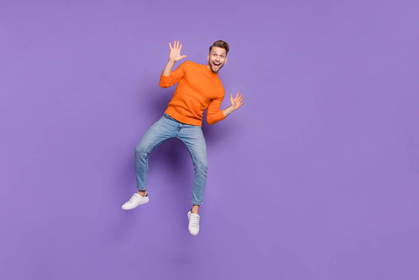 Full length photo of good mood overjoyed male jumping up wave hands say hi meet friend isolated on violet color background - 写真・画像