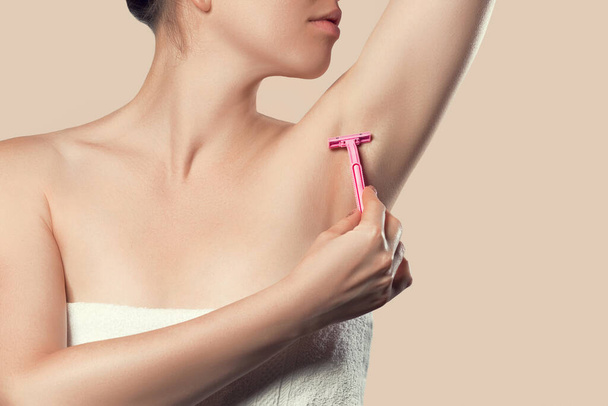 Жінка м'яко голиться пахвою епіляції видалення волосся з ергономічним рожевим голінням. Догляд за шкірою тіла концепція краси
 - Фото, зображення