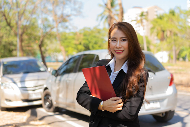 Asian women are insurance agents holding clipboards and standing in front of car accidents after checking car damage, Concepts of insurance, and car traffic accidents. - Photo, Image