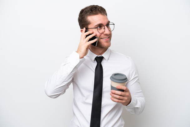 Young business caucasian man isolated on white background holding coffee to take away and a mobile - Valokuva, kuva