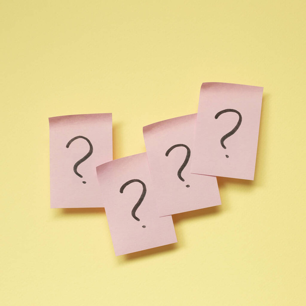 Question mark on pink memo paper on yellow background - Foto, imagen