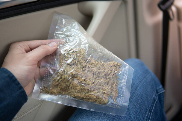 fleurs de cannabis. broyeur et joint de cannabis déchiqueté paquet de mauvaises herbes sur un fond de voiture fermer bourgeon de marijuana - Photo, image