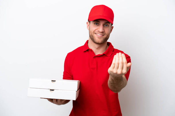 Dostawa pizzy mężczyzna kaukaski z munduru pracy podnosząc pudełka pizzy izolowane na białym tle zapraszając przyjść z ręką. Cieszę się, że przyszedłeś. - Zdjęcie, obraz