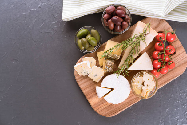 Charcuterie board with cheese slices and assortment of traditional Italian antipasti, cheese plate on dark concrete background with copy space - Photo, Image