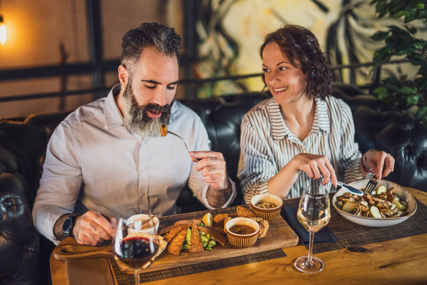  La coppia felice e 'seduta al ristorante. Stanno cenando con il vino e trascorrendo del tempo insieme. - Foto, immagini