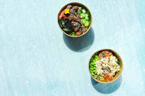 Top view of wok box, bowl of rice on black background. Rice fried and stirred with salmon, avocado, onion, mushrooms, broccoli, sesame. Chinese, Asian food delivery. Packaging for woks.  - Foto, Imagen